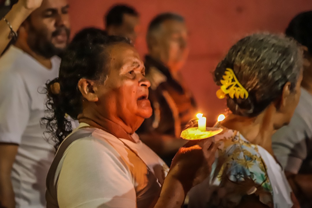Foto de fiel na procissão segurando uma vela